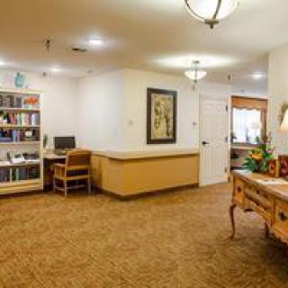 A cozy reception area with a desk, bookshelf, and warm lighting.