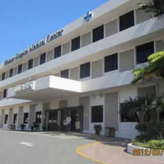 The front entrance of a modern hospital building on a sunny day.
