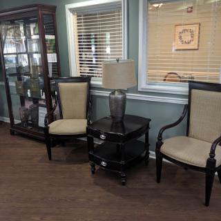 A cozy seating area featuring two chairs, a side table with a lamp, and a display cabinet.