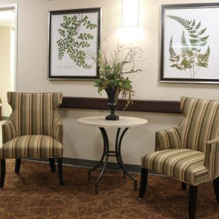 A cozy waiting area with two striped chairs, a small round table, and botanical artwork.