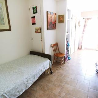 A simple bedroom with a single bed, artwork on the walls, and abundant natural light.