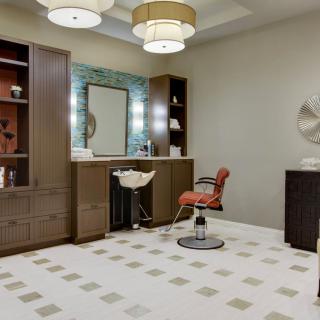 A modern hair salon interior with stylish furniture, soft lighting, and a large mirror.