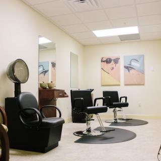 A modern salon interior with styling chairs, mirrors, and wall art.