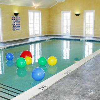 An indoor swimming pool with colorful beach balls floating on the water.