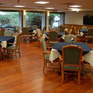 An empty dining room with neatly arranged tables and chairs on a wooden floor.