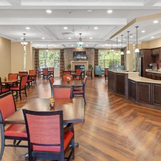 A spacious dining area with wooden tables and red chairs, featuring ceiling lights and a hardwood floor.