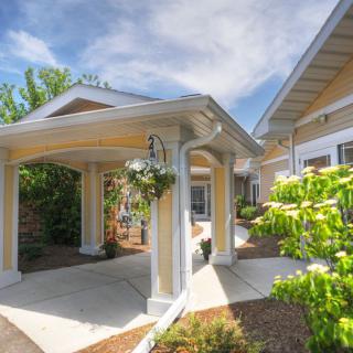 A beautifully designed house entrance with a garden and a canopy.