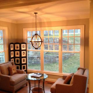 A cozy living room with ample natural light, featuring two chairs and a small table by large windows.