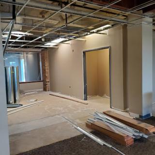 A view of an office space undergoing renovation, featuring exposed ceilings and walls ready for finishing.