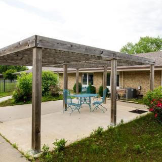 A backyard patio with a wooden pergola and outdoor seating.