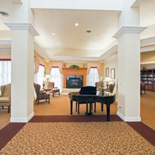 A spacious lobby area featuring a grand piano and cozy seating arrangements around a fireplace.