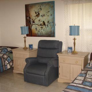 A cozy living room with an armchair, two lamps on nightstands, and artwork on the wall.