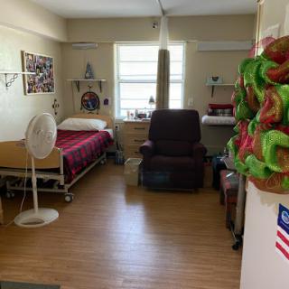 A view of a patient's room in a hospital, featuring a bed, recliner chair, and personal touches.