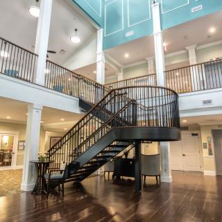 A modern interior featuring a grand staircase with wooden flooring and an open balcony design.
