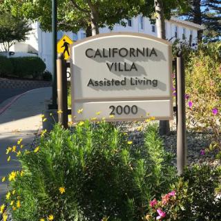 A sign for California Villa Assisted Living surrounded by greenery.