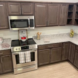 A modern kitchen with brown cabinets, stainless steel appliances, and a neatly organized countertop.