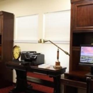 A traditional office setup featuring wooden furniture, a computer, and a desk lamp.