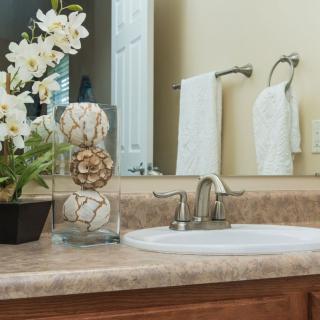 A neatly arranged bathroom countertop with decorative flowers and towels.