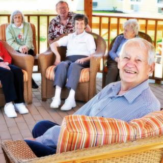 A group of elderly people enjoying social time together outdoors.