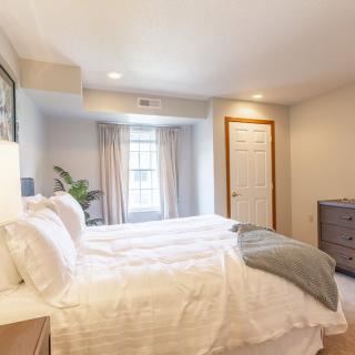 A cozy, modern bedroom with a neatly made bed and bright natural light.