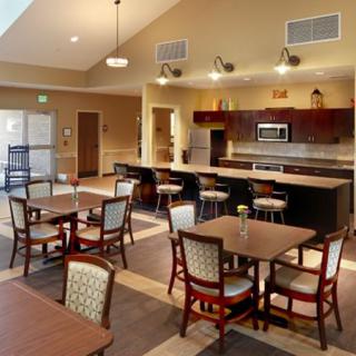 A cozy dining area with multiple tables and chairs, adjacent to a kitchen.