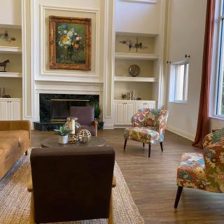 A cozy living room with elegant furniture, artwork above the fireplace, and built-in shelves.
