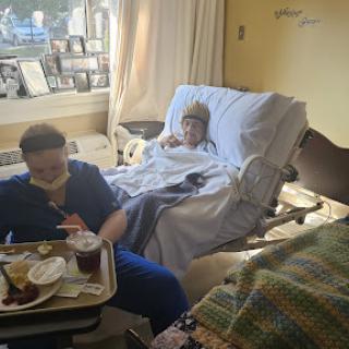 A nurse assists a patient in a hospital room, providing care and support during recovery.