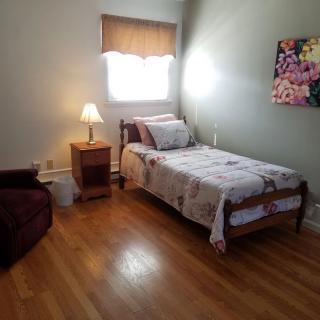 A cozy bedroom with a single bed and wooden flooring.