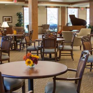 A cozy lounge area featuring tables, chairs, and a grand piano.