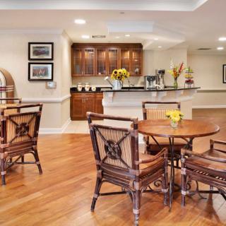 A cozy dining area featuring wooden tables and chairs with a view of a modern kitchen in the background.