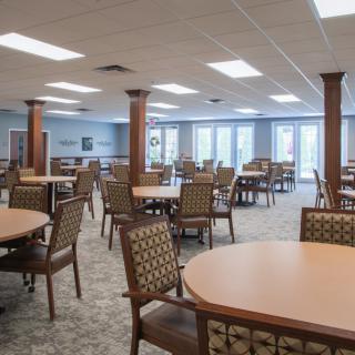 A spacious dining area with multiple tables and chairs arranged neatly under bright lighting.
