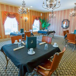 Elegant dining room with chandeliers and formal table settings.