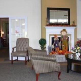 A cozy living room with striped chairs, a central coffee table, and a decorated fireplace.