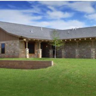 A modern house with a brick exterior and a spacious green yard under a clear blue sky.