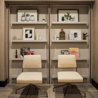 Modern interior with two chairs in front of a decorative bookshelf.