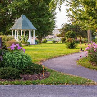 A picturesque garden featuring a charming gazebo surrounded by vibrant flowers and well-maintained greenery.