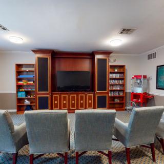 A cozy home theater with plush chairs, a large television, and built-in bookshelves.