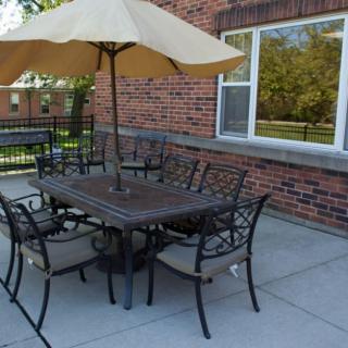 A patio setup with a table, chairs, and an umbrella near a brick building.
