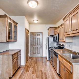 A modern kitchen with wooden cabinets, stainless steel appliances, and a hardwood floor.