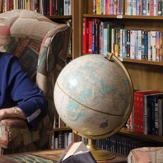 A cozy library with a globe on a table and bookshelves filled with books.