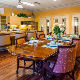 A well-decorated dining room with a set table and an adjoining kitchen area.