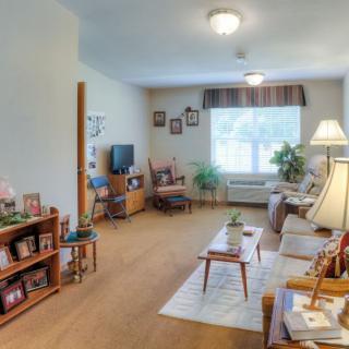 A cozy and well-lit living room with comfortable furniture, decorative elements, and a large window with curtains.