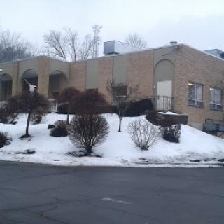 A cozy building surrounded by snow and winter foliage.