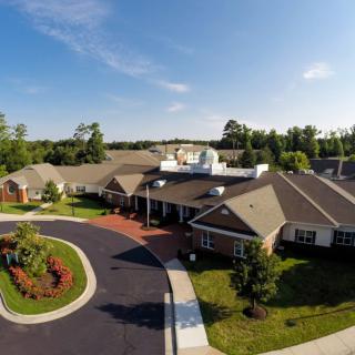 Aerial view of a suburban building surrounded by landscaped gardens and a driveway.
