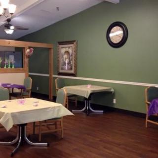 An indoor dining area with tables and chairs, featuring green walls and decorations.