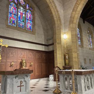 A serene view of the altar in a church featuring beautiful stained glass windows.