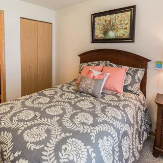 A cozy bedroom with a floral-patterned bedspread, decorative pillows, and framed artwork above the bed.