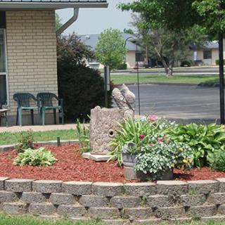 A well-maintained garden with a stone feature and various plants surrounded by mulch.