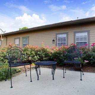 A cozy patio set with two chairs and a table surrounded by vibrant flowers in an outdoor garden setting.