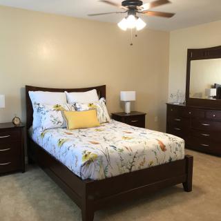 A well-furnished bedroom with a bed, dresser, and lamp.